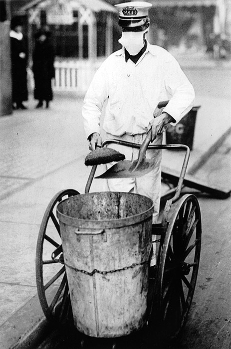 A New York City street sweeper goes about his business while wearing a gauze mask to guard against influenza, October 16, 1918.