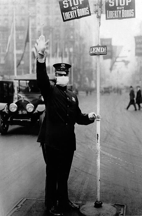 A New York City traffic cop directs vehicles while wearing a flu mask, October 16, 1918.