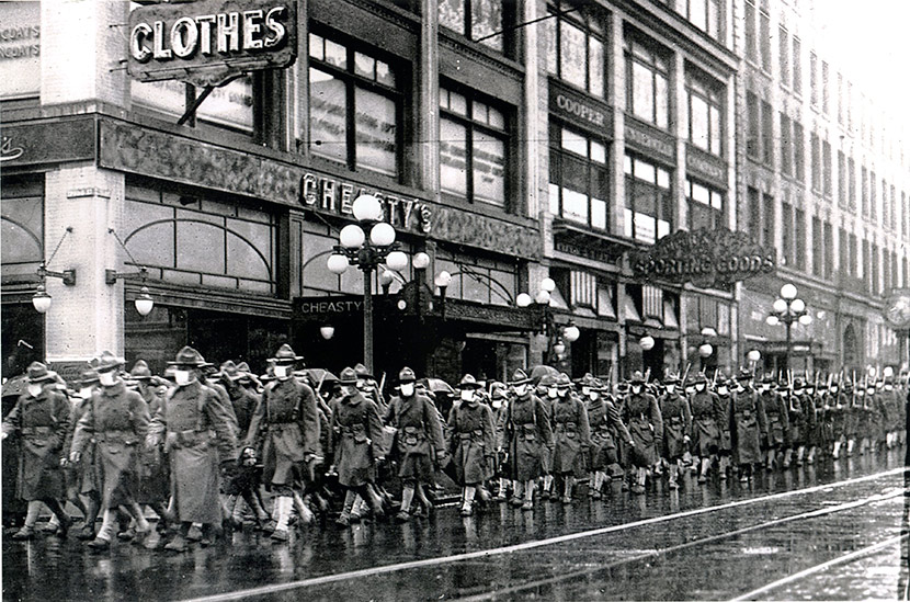 The 39th Regiment marches down 2nd Ave. with their flu masks on, passing Cheasty’s Haberdashery, ca. October/November 1918.