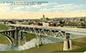 A view of the Oregon-Washington Railroad and Navigation Company bridge and the Monroe Street Bridge crossing the Spokane River, with the city in the background.