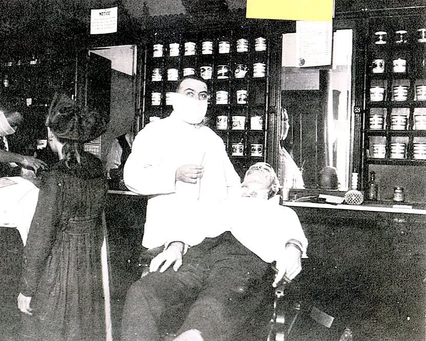 A Cincinnati barber wears a mask while giving a customer a shave.