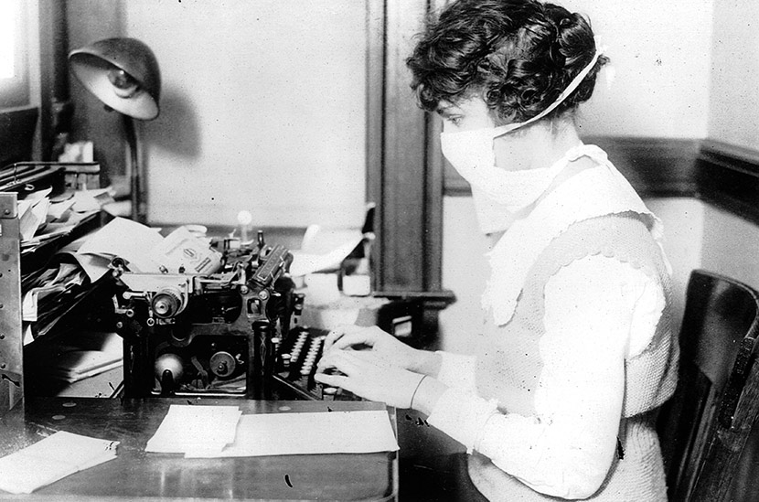 A New York City typist wears a flu mask while at her desk, October 16, 1918.