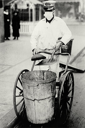 A New York City street sweeper goes about his business while wearing a gauze mask to guard against influenza, October 16, 1918.