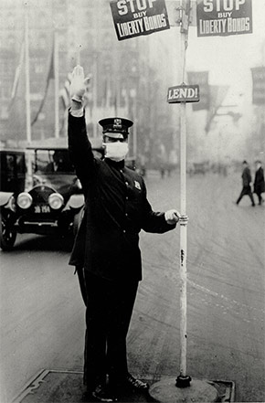 A New York City traffic cop directs vehicles while wearing a flu mask, October 16, 1918.
